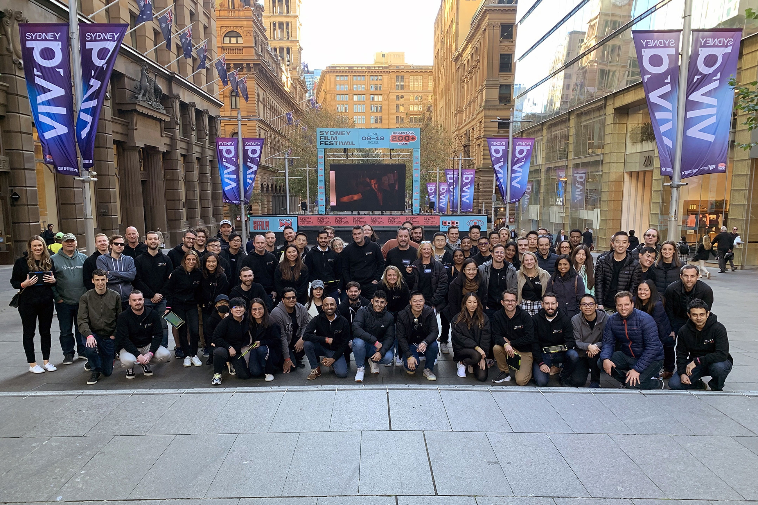 Photo of a large group of mx51 employees posing and smiling together at Martin Place, Sydney.