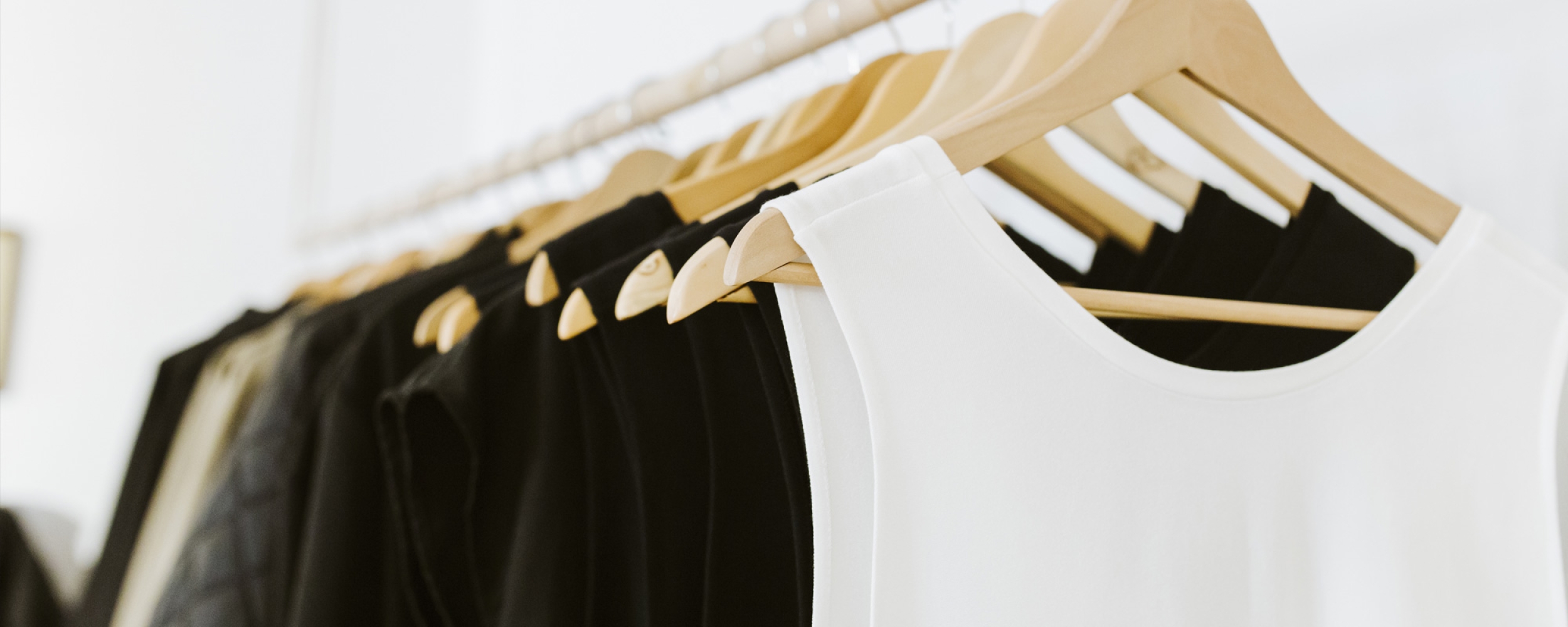 Close-up photo of a rack of clothing on the same timber hangers.
