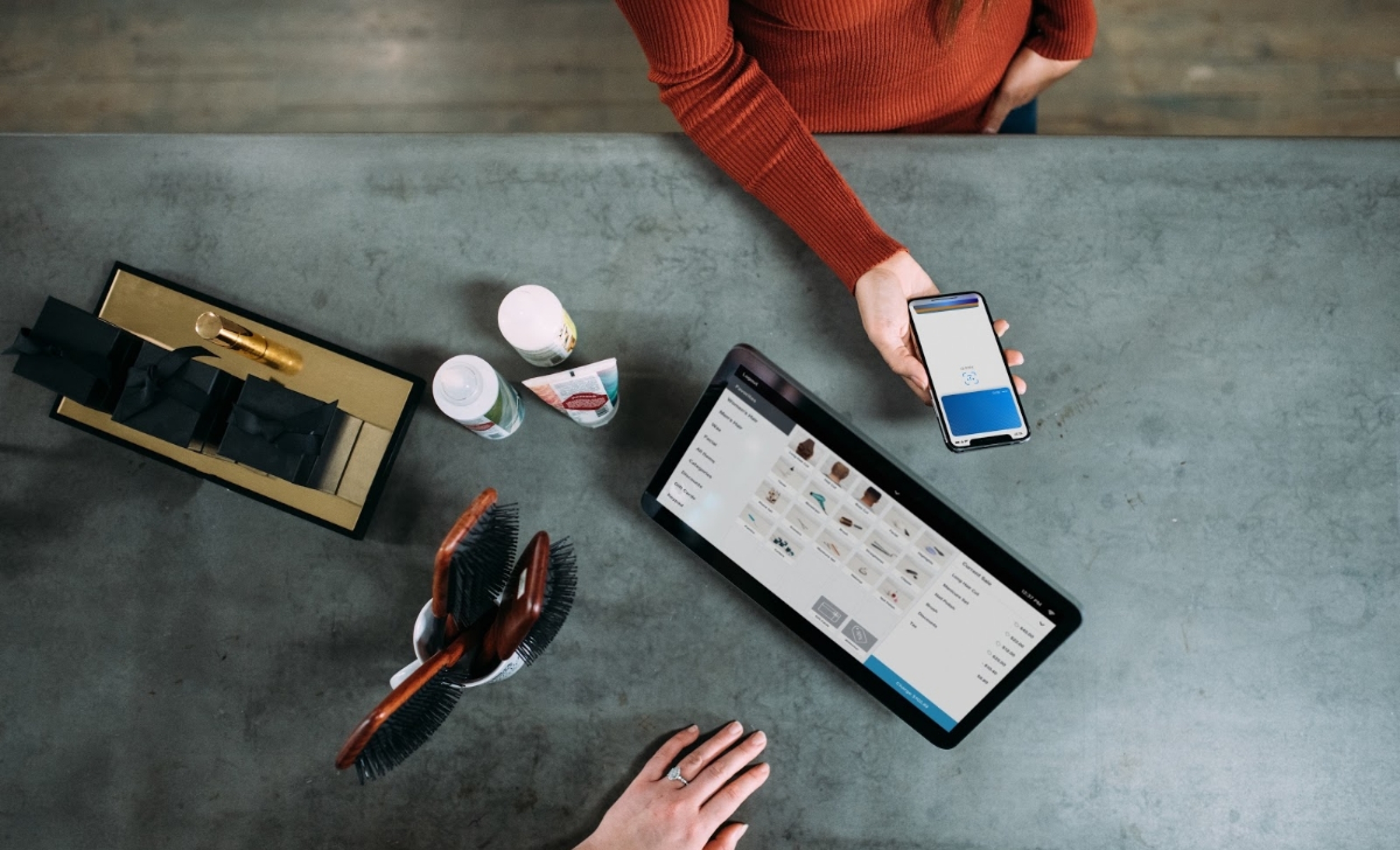 Image from above, looking at a customer paying with their phone while a business owner looks at their computer screen.