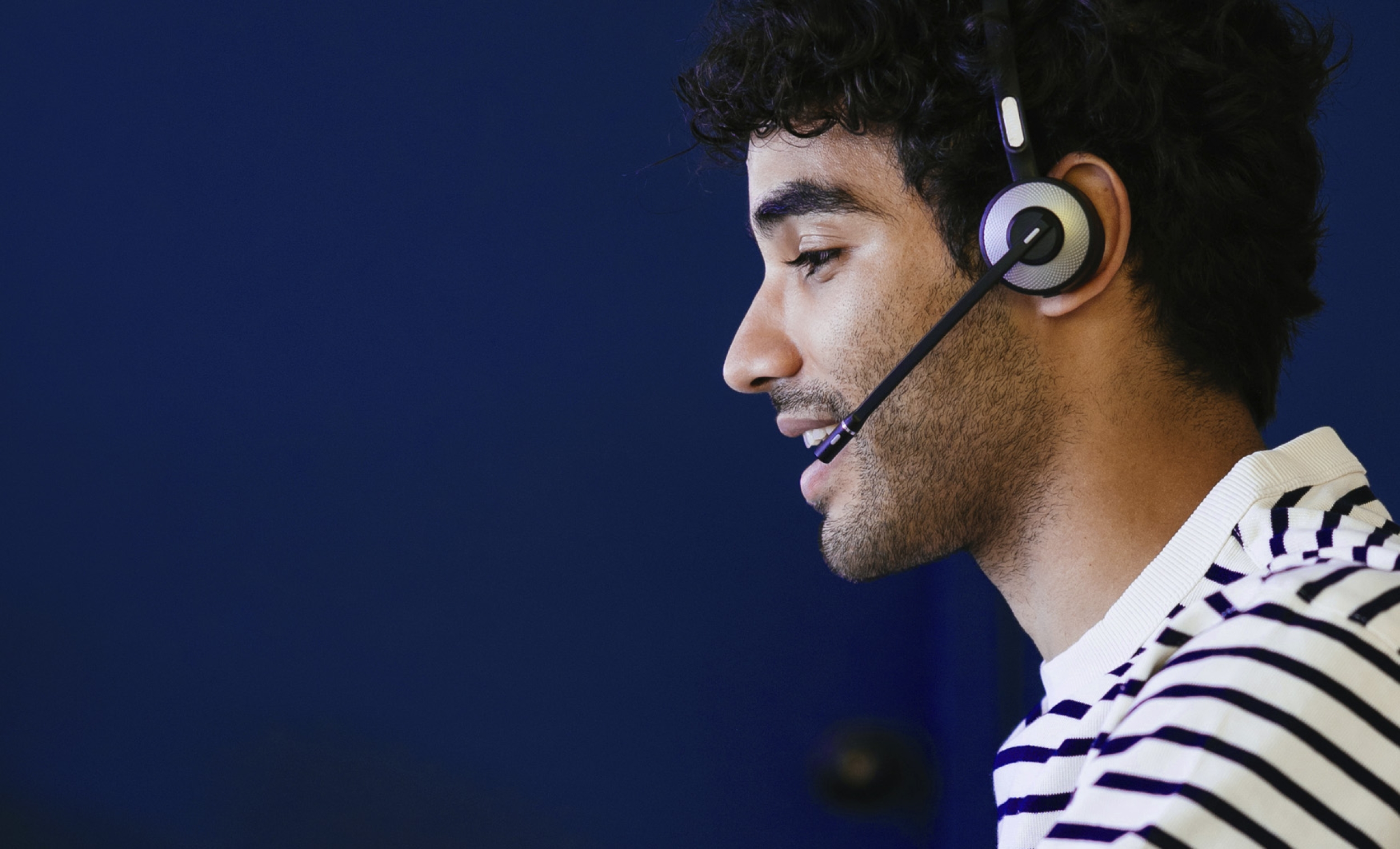 A friendly looking customer service representative is sitting down while wearing a headset.