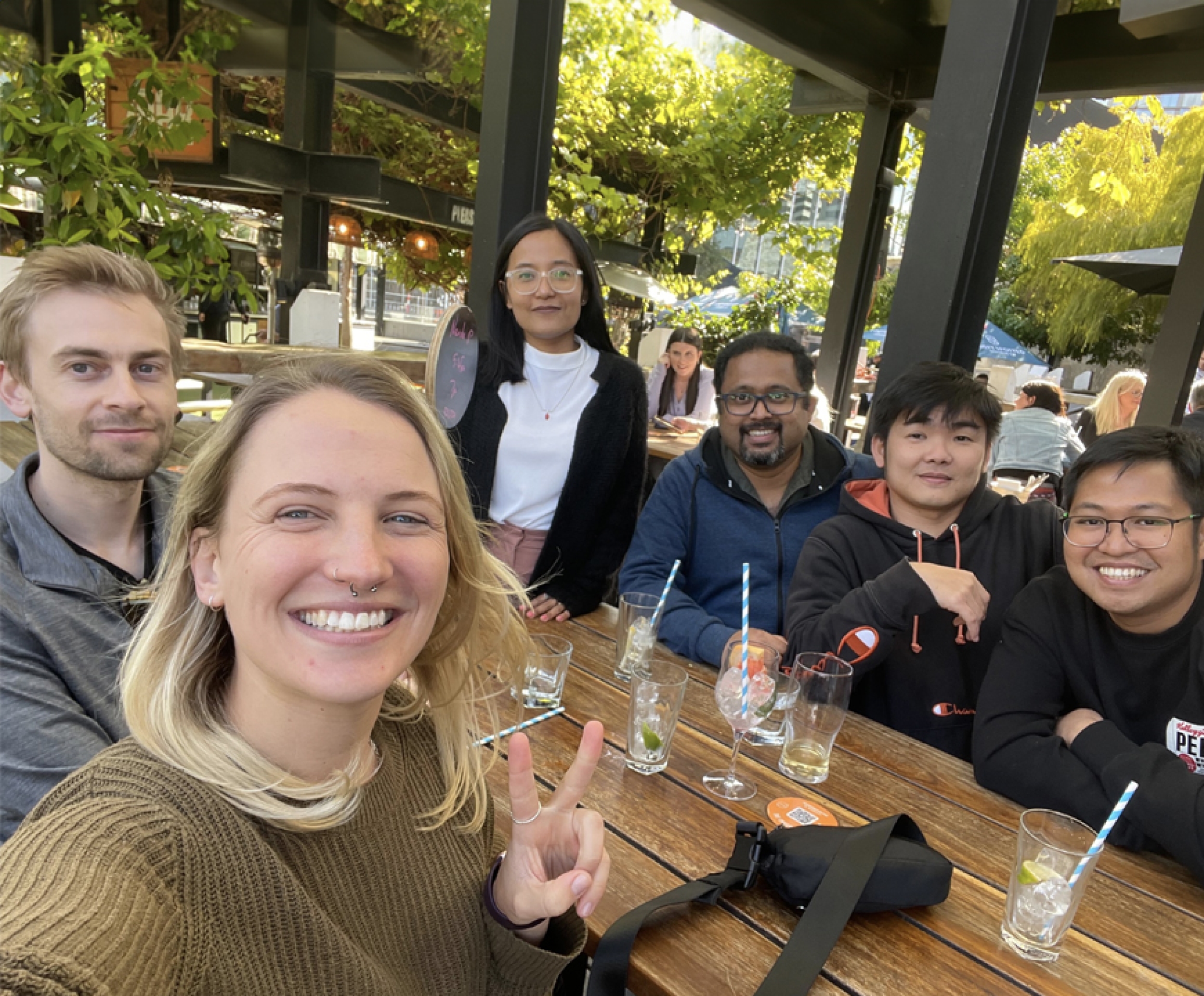 Snapshot of a small group of smiling mx51 colleagues having a drink at a table outside.