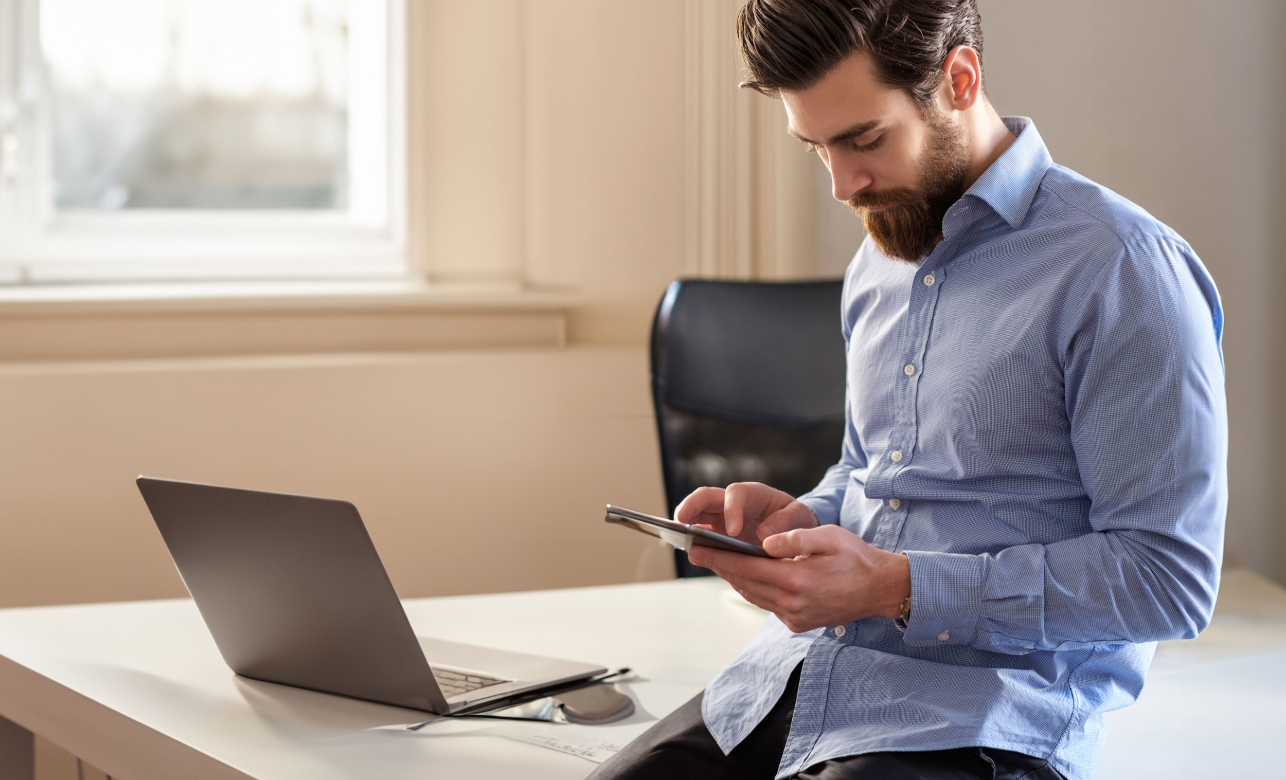 Office worker wearing a light blue shirt, looking at an iPad.
