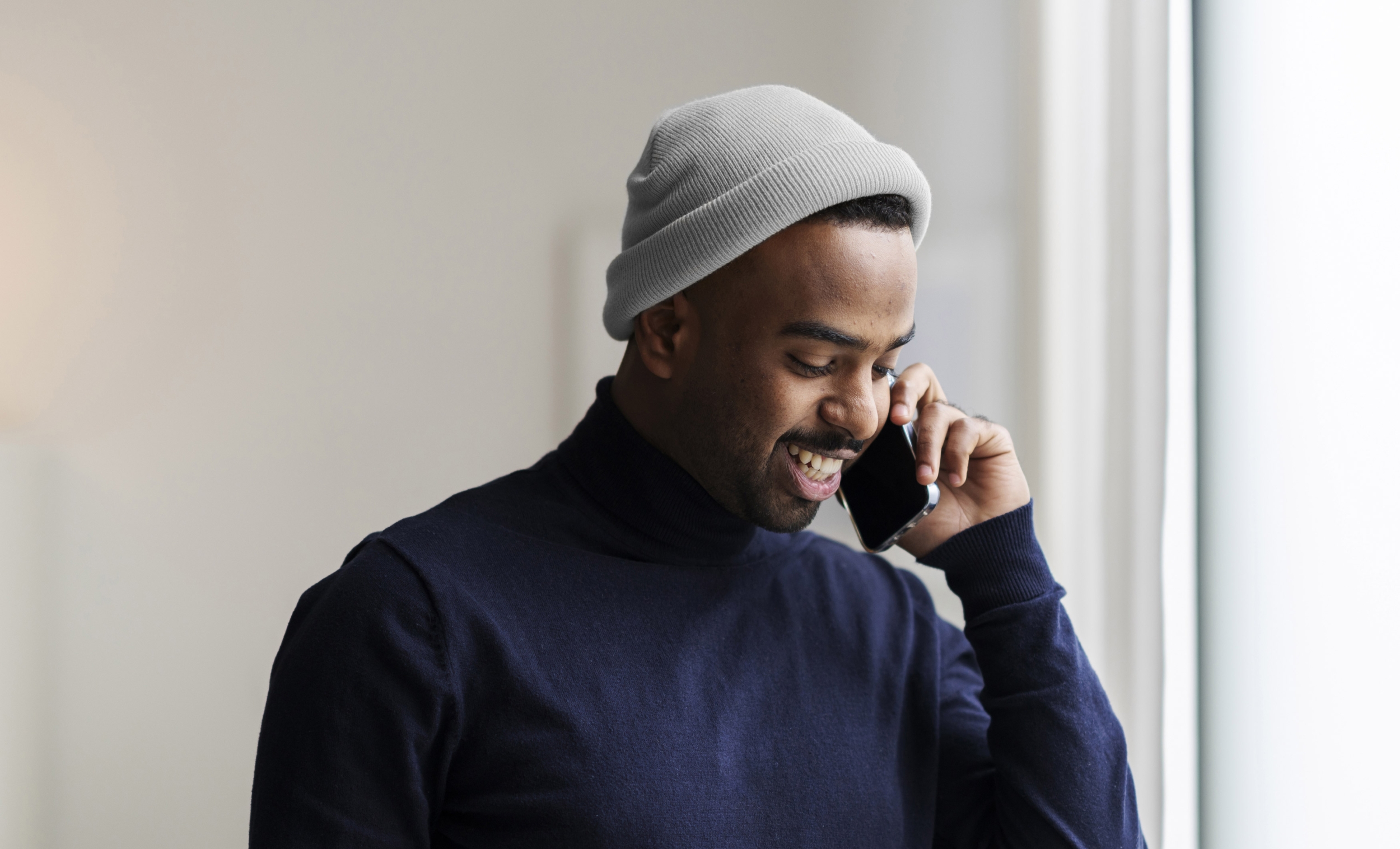 Attractive young black man is making a phone call and smiling.