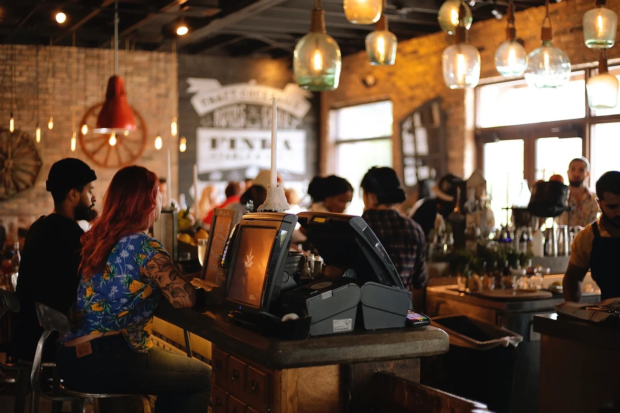 Image of a busy bar with multiple payments devices and computer screens.