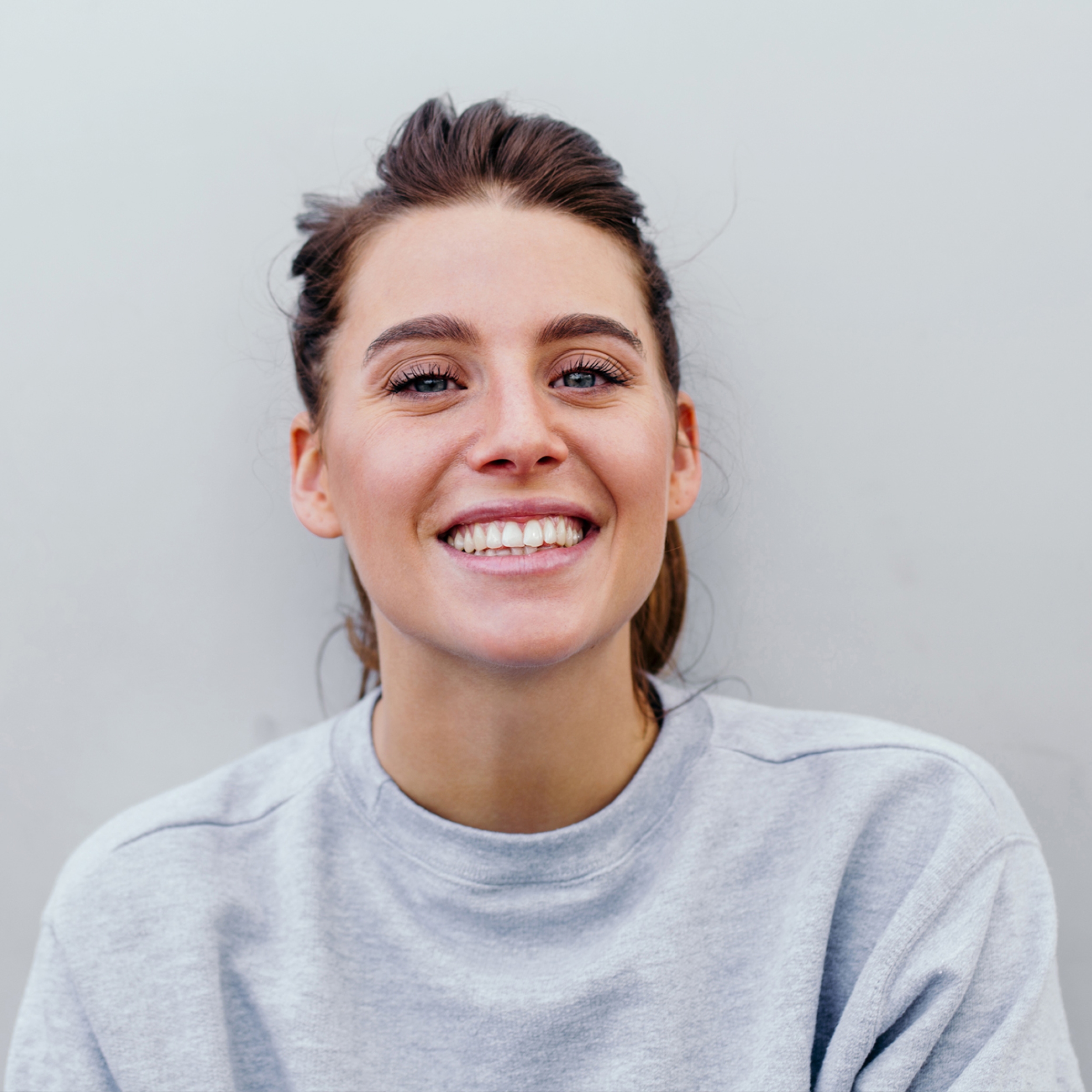 Image of a young attractive woman wearing a grey sweater and smiling at the camera.
